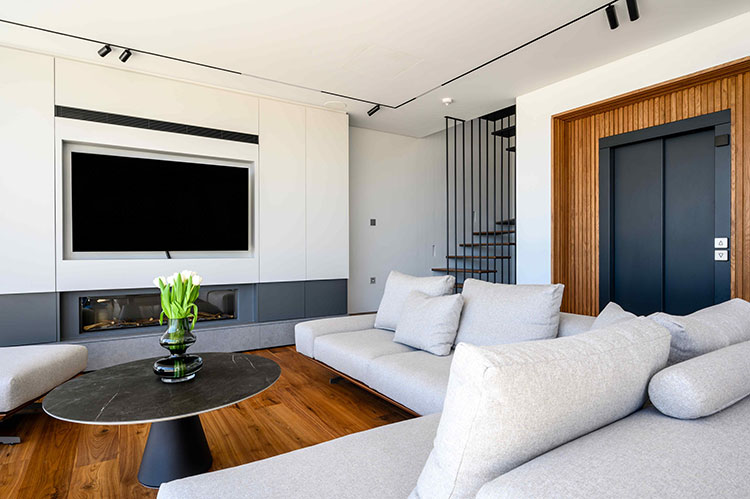 Επένδυση τοίχου με λακαριστό έπιπλο ντουλάπα που φιλοξενεί την τηλεόραση και το ενεργειακό τζάκι αερίου