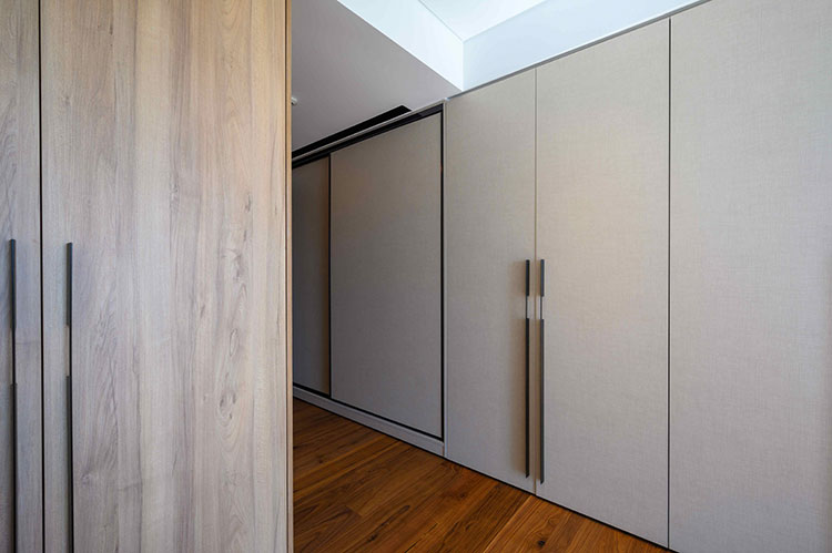 Συρόμενες και ανοιγόμενες ντουλάπες με επιφάνειες σε εφέ λινό ύφασμα και μεγάλα μεταλικά πόμολα